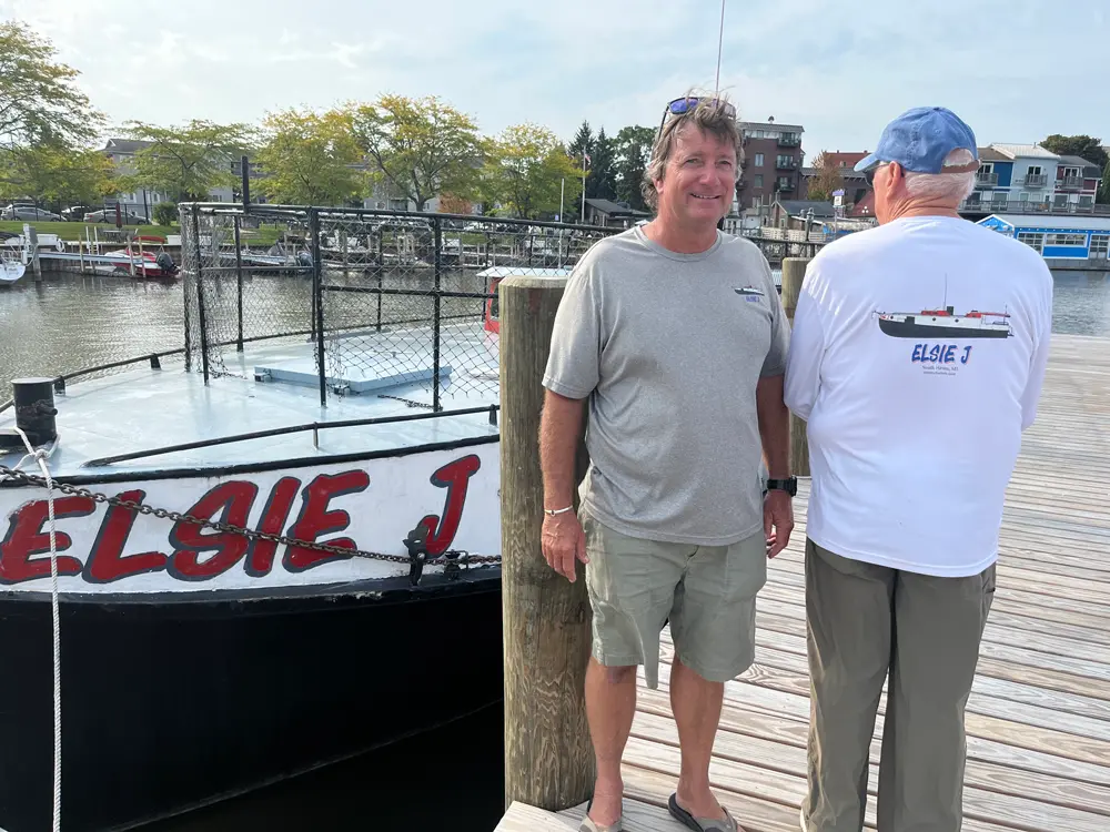 Everyone loves the shirts. Thanks! An image of a custom yacht shirt customer wearing their custom gear next to their vessel.