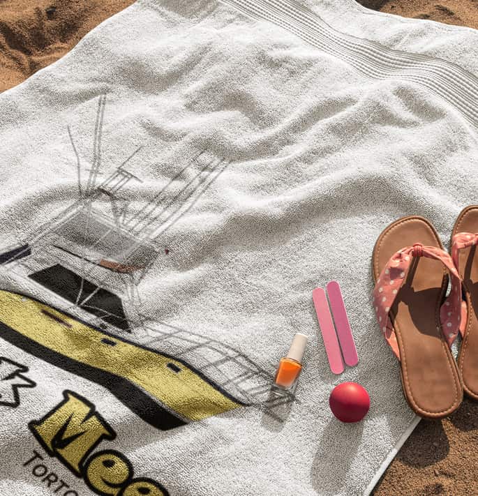 An image of a custom beach towel with boat from custom yacht shirts