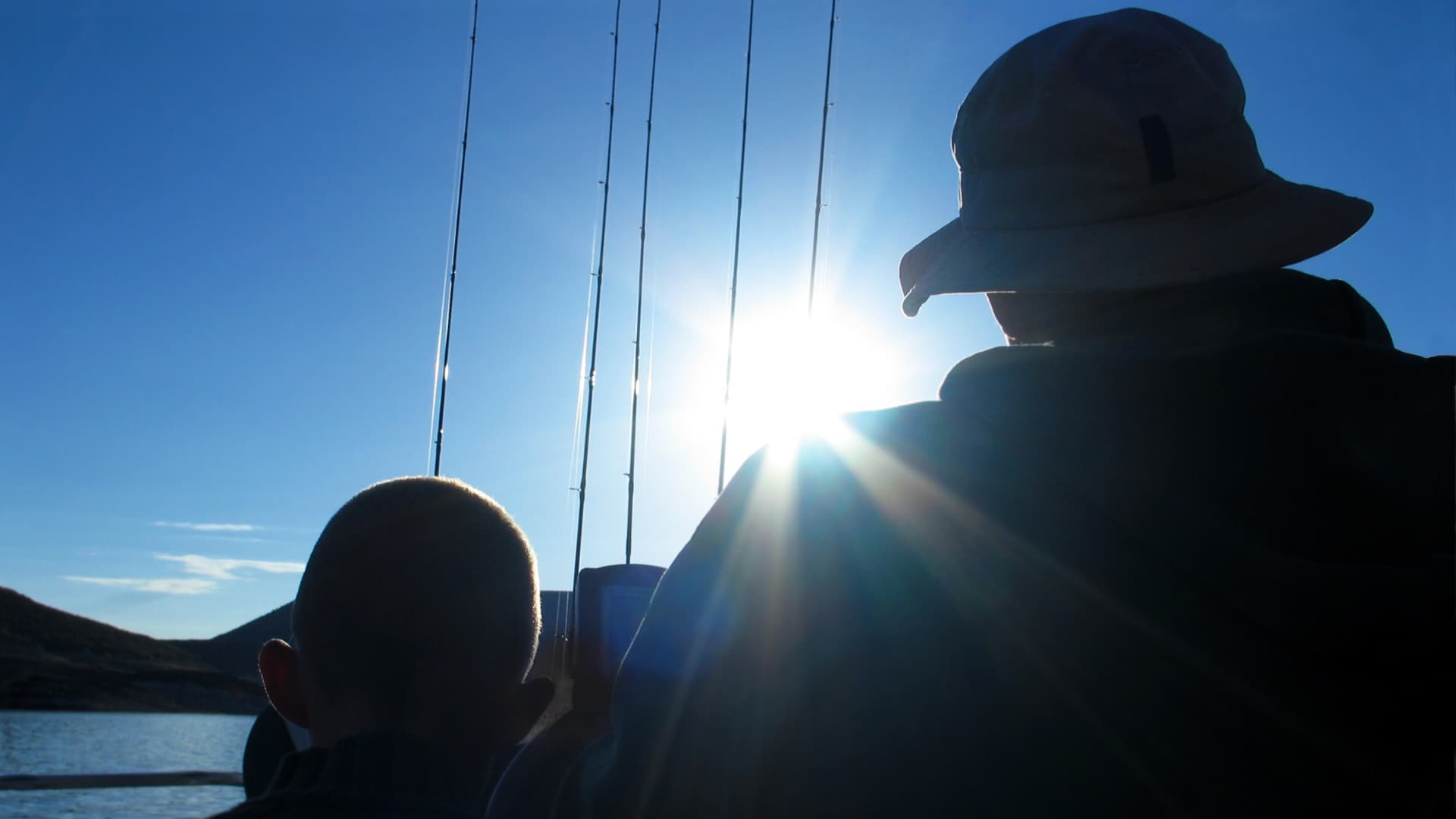 An image of a father and son going fishing with dad wearing a fishing hat. 