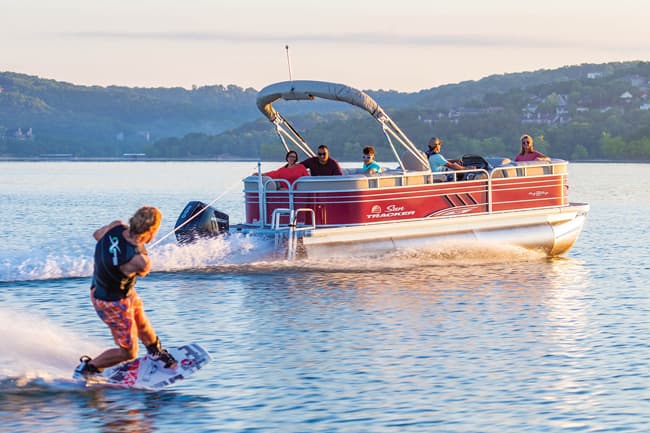 An image of a person wakeboarding behind a suntracker pontoon boat