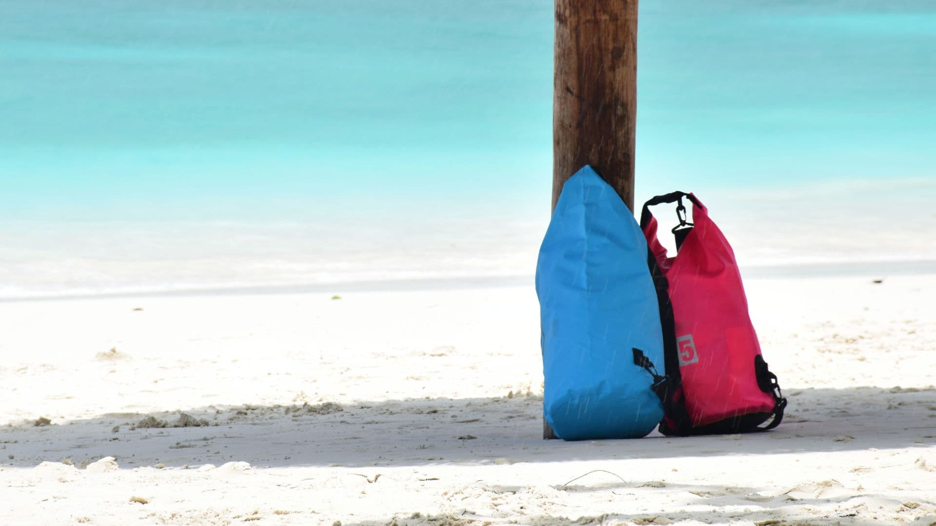 An image of two waterproof bags for boating on a beach.