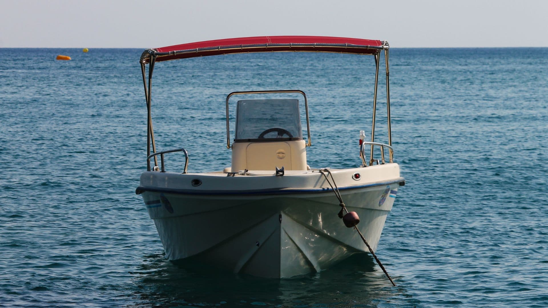 A boat with a red bimini top sits at mooring. 