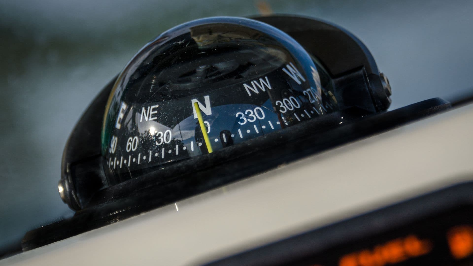 An image of a black boat compass pointing due north on a boat. 