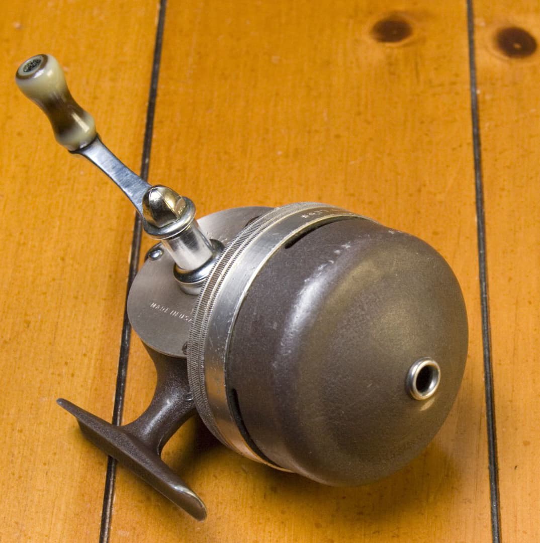 Spincast fishing reel on a wooden dock background. 